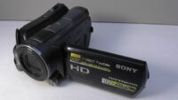 filmadora sony hdr-sr12 usada com anel pequeno multifuncional para controle rápido de ajustes manuais.